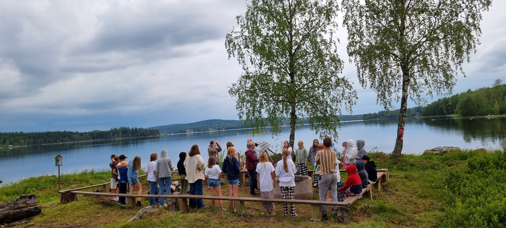 Lägerdeltagare samlade vid eldstaden med utsikt över Liljan