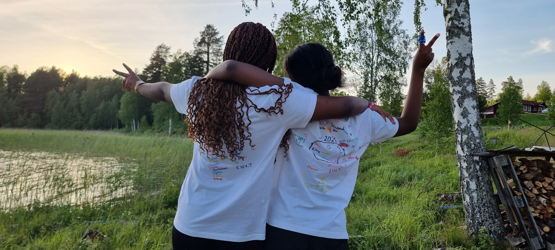 Två lägervänner med signerade t-shirts i solnedgång vid sjön