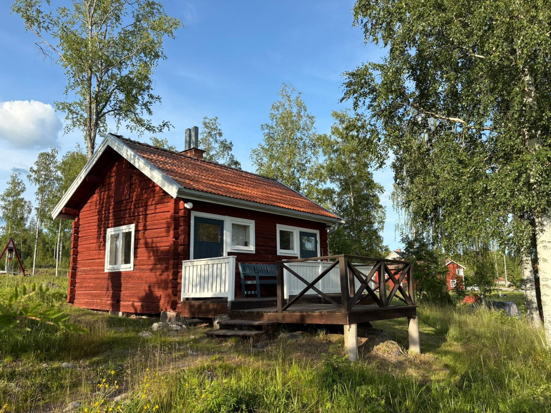 Röd stuga med altan på Dalagården en sommarkväll